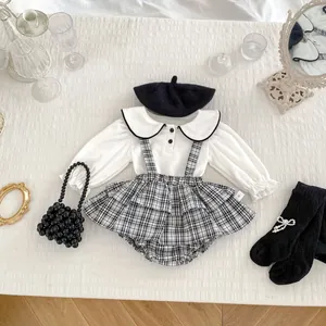 Dettaglio flat lay del set neonata a quadri con camicia bianca e borsa di perle