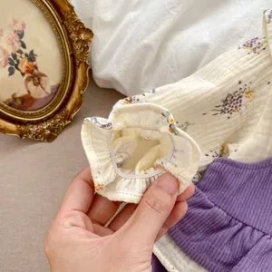 Detail of floral baby blouse ruffle cuff and purple corduroy fabric texture