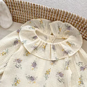 Detail of floral infant blouse featuring ruffled collar and soft cotton texture