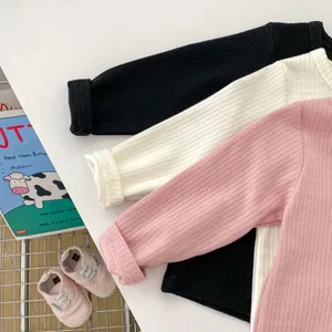 Detail von gerippten Langarm-Babyshirts in den Farben Rosa, Weiß und Schwarz