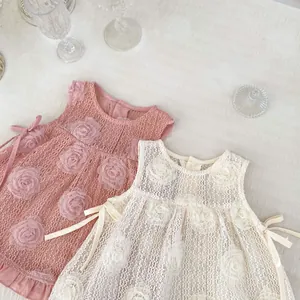 Détail d'une robe bébé avec appliques florales 3D et nœuds décoratifs sur le côté