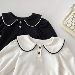 Dettaglio di camicie da neonata con colletti Peter Pan e profili a contrasto bianco e nero