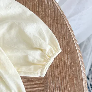 Détail du poignet élastique d'un body bébé crème en coton sur une surface en bois rustique