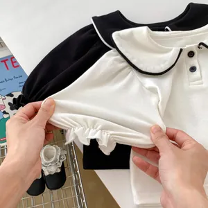 Dettaglio dei polsini elastici con volant su camicie in cotone per neonati in bianco e nero