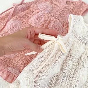 Détail des appliques de roses 3D et des nœuds en satin sur le body en tulle rose bébé