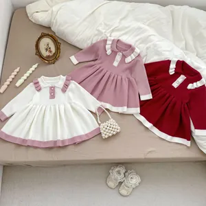 Flat lay of knit baby dresses with ruffle Peter Pan collars in various autumn colors