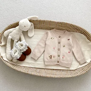 Dettaglio del ricamo floreale su cardigan in maglia per neonati con bottoni in legno