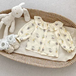Close-up of baby floral blouse with ruffled collar and matching lace shoes in a cradle