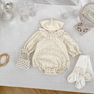 Vue à plat de la barboteuse fleurie bébé avec col volanté, béret, chaussettes et petit sac