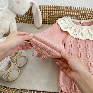 Detailansicht eines rosa Baby-Strickbodys mit Spitzenkragen und Zopfmustern
