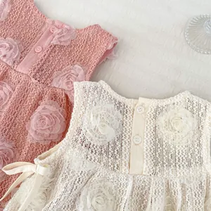 Détail de robe bébé avec fleurs en dentelle 3D, tissu ajouré et boutons ronds