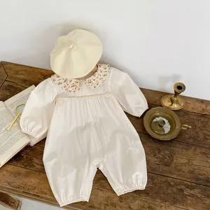 Barboteuse bébé à imprimé fleuri avec col et béret en tricot sur fond de bois vintage
