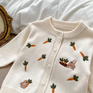 Détail du cardigan tricoté pour bébé avec broderie carotte et lapin et boutons blancs