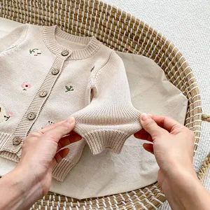 Dettaglio del ricamo floreale su cardigan in maglia per neonati con bottoni in legno