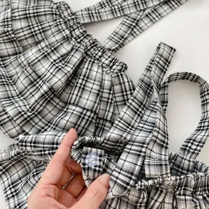 Dettaglio del vestito a quadretti bianchi e neri per neonata con bottone trasparente