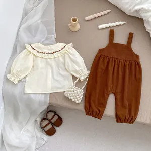 Detail von Baby-Mädchen Bluse mit Spitzenkragen und Cord-Latzhose mit Stickerei