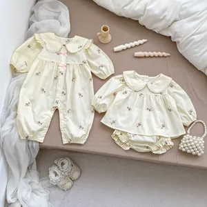 Dettaglio pagliaccetti neonato a fiori con colletti Peter Pan e fiocchi rosa sul letto