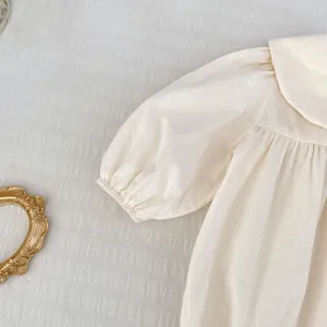 Détail d'une robe bébé avec col Peter Pan et manches bouffantes en coton respirant