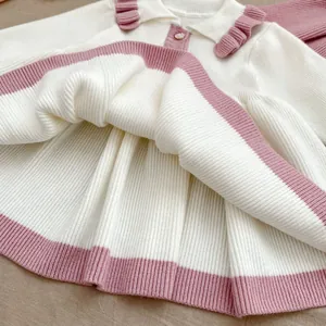 Detail of knit girl dress featuring pink ruffled collar and pearl button closure