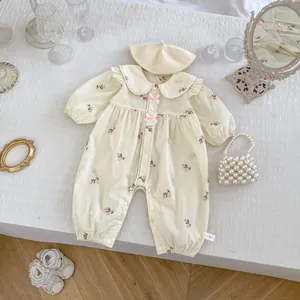 Dettaglio di pagliaccetto ricamato color crema per neonati con cuffia e scarpine di pizzo