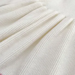 Macro shot of white ribbed knit fabric texture on a soft girl's long sleeve princess dress