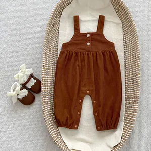 Detail von Baby-Cord-Strampler mit Knöpfen und passenden Schleifenschuhen im Weidenkorb
