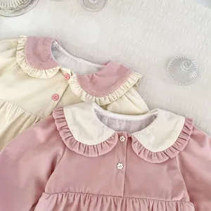 Detailed view of baby girl dresses with ruffle collars and flower buttons in velvet fabric