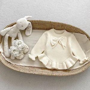 Detalle de suéter de punto gofrado para bebé en color crema con volantes y zapatos a juego