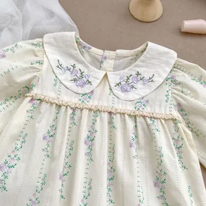 Detail of floral baby bodysuit with Peter Pan collar and delicate purple flower embroidery