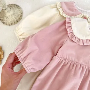 Detail view of pink and beige corduroy baby dresses with Peter Pan collars and ruffles