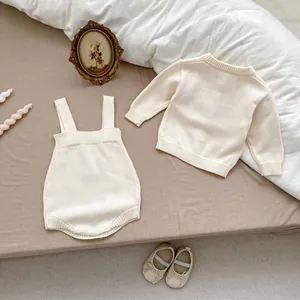 Détail de l'ensemble de tricot pour bébé crème avec poignets côtelés sur literie douce
