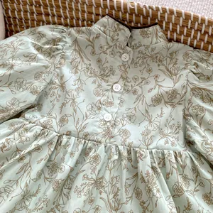 Detail of floral baby bodysuit with mandarin collar, puff sleeves, and button accents
