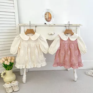 Détails de broderie florale sur robes bébé rose et crème avec manches bouffantes