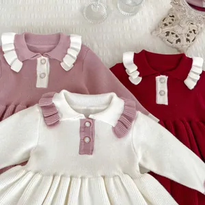 Detail of baby girl knitted dresses with ruffled collars and gold-rimmed pearl buttons