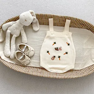 Détail de barboteuse tricotée pour bébé avec broderie lapin dans un panier tissé