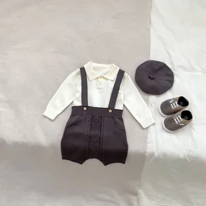 Detail of baby boy knit outfit with beige polo sweater and brown overall shorts
