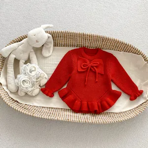 Detalle de jersey de punto rojo para bebé con lazo y volantes en una cuna tejida