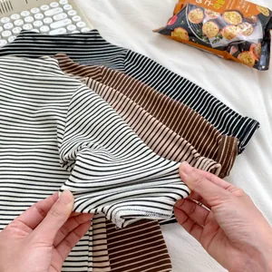 Detail shot showing the high elasticity of striped long sleeve baby shirts in soft cotton