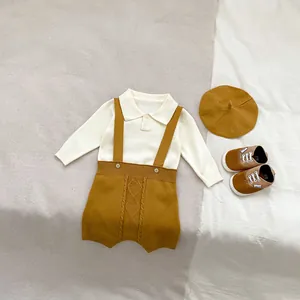 Detail of baby knit set featuring textured yellow suspenders and beige sweater