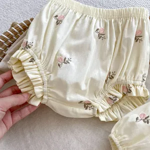 Dettaglio del tessuto in cotone crema con ricami di fiori rosa e orli con volant