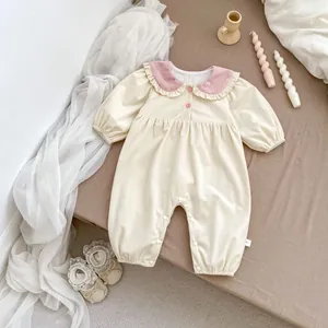 Detail of corduroy baby romper featuring ruffles and snap buttons on a warm background