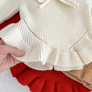 Jersey de punto de nido de abeja para niña con volantes y lazo en marfil, rojo y marrón