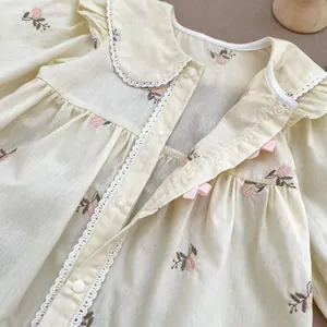 Dettaglio body neonata con ricami floreali, colletto in pizzo e chiusura con bottoni