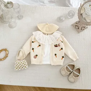 Détails à plat du cardigan tricoté pour bébé avec broderie carotte et béret assorti