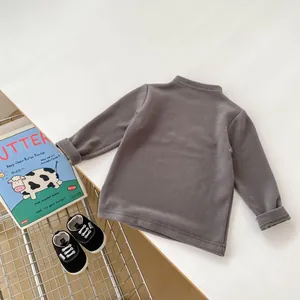 Flat lay of a grey velvet long-sleeve baby shirt with matching monochrome soft-sole shoes