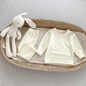 Soft cream thermal fleece baby pajamas set in a cozy woven basket with plush toy