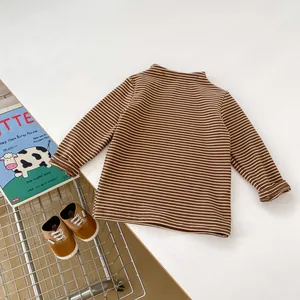 Flat lay of brown striped baby long sleeve shirt with flexible mock neck and storybook