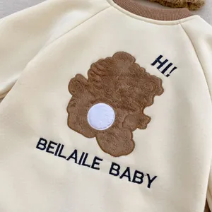 Gros plan d'une broderie ours brun avec texture pelucheuse sur barboteuse bébé