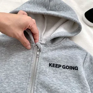 Detail of grey fleece zip-up hoodie featuring Keep Going letter print and smooth metal zipper