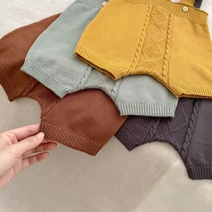 Detailed cable knit patterns and wooden buttons on assorted infant knitted rompers